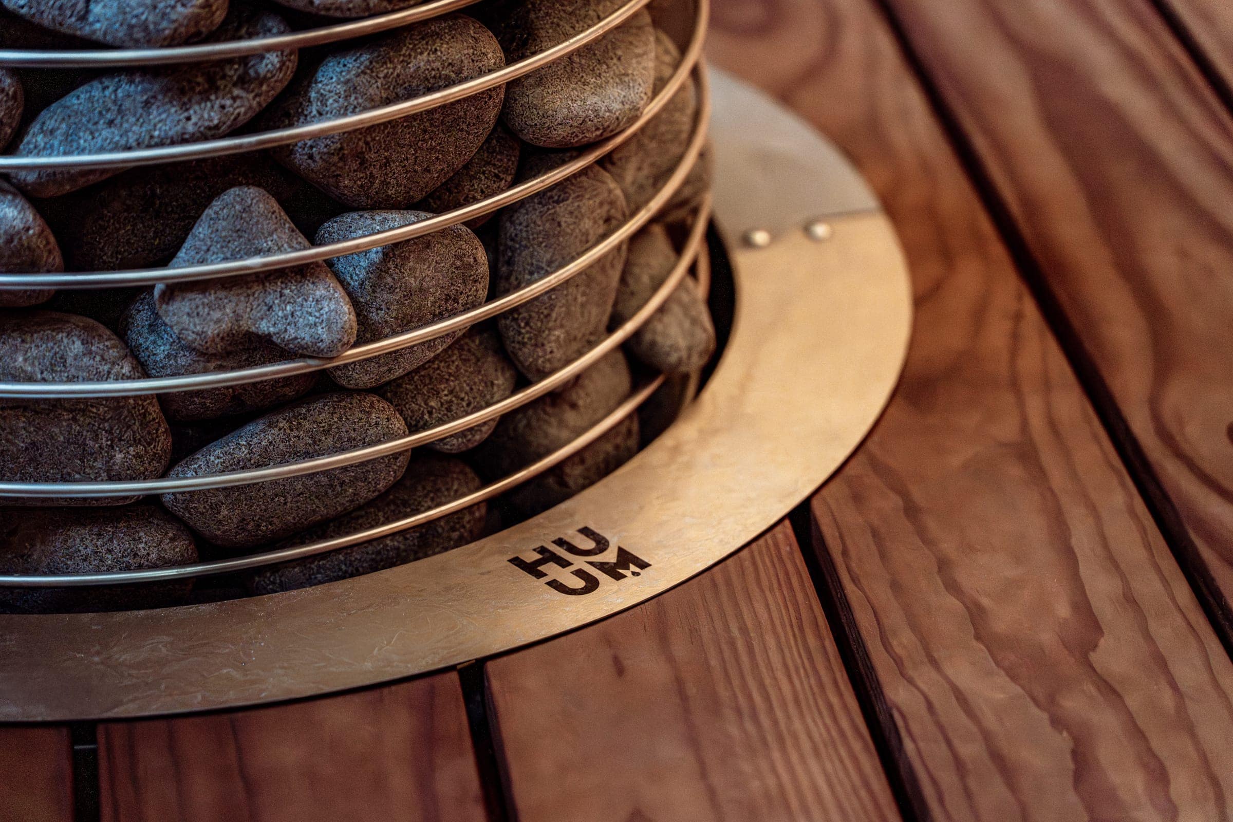 The HUUM HIVE's base sunk into a steel collar in a wooden sauna floor
