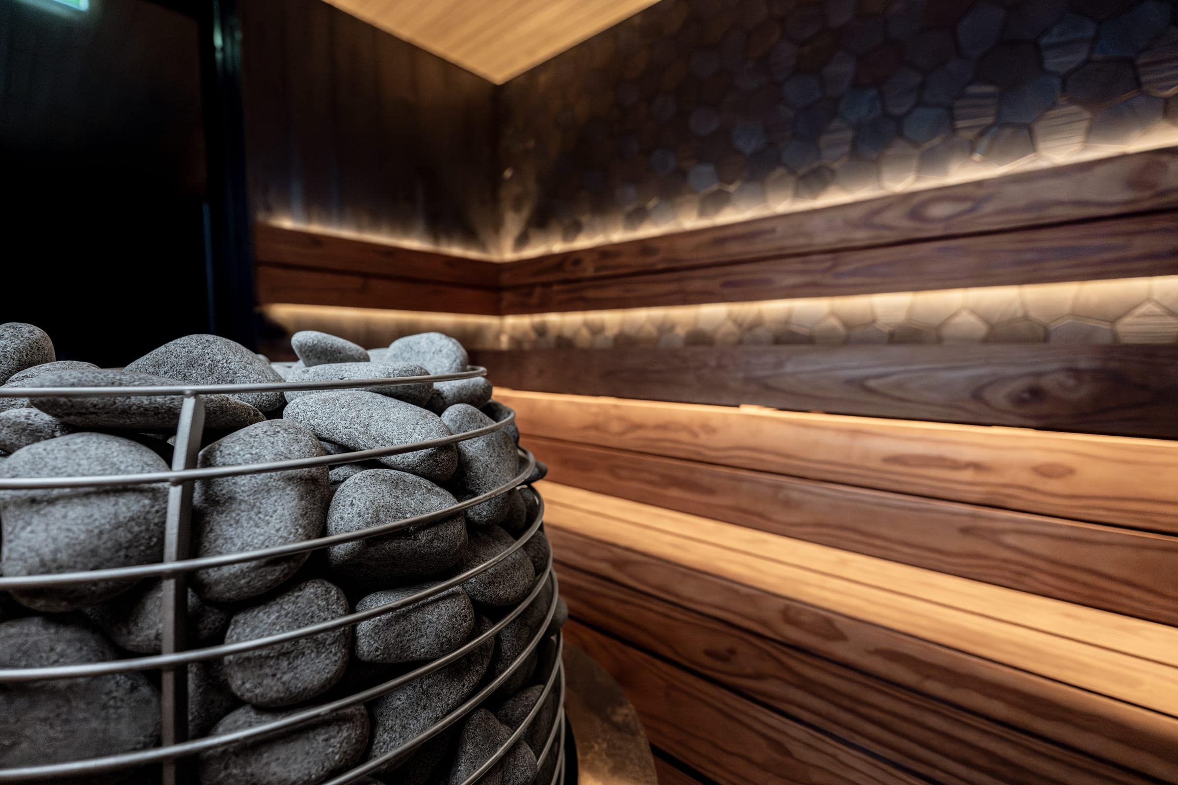 Close-up of the HUUM HIVE's steel rings and stones with warm-lit tiered benches behind