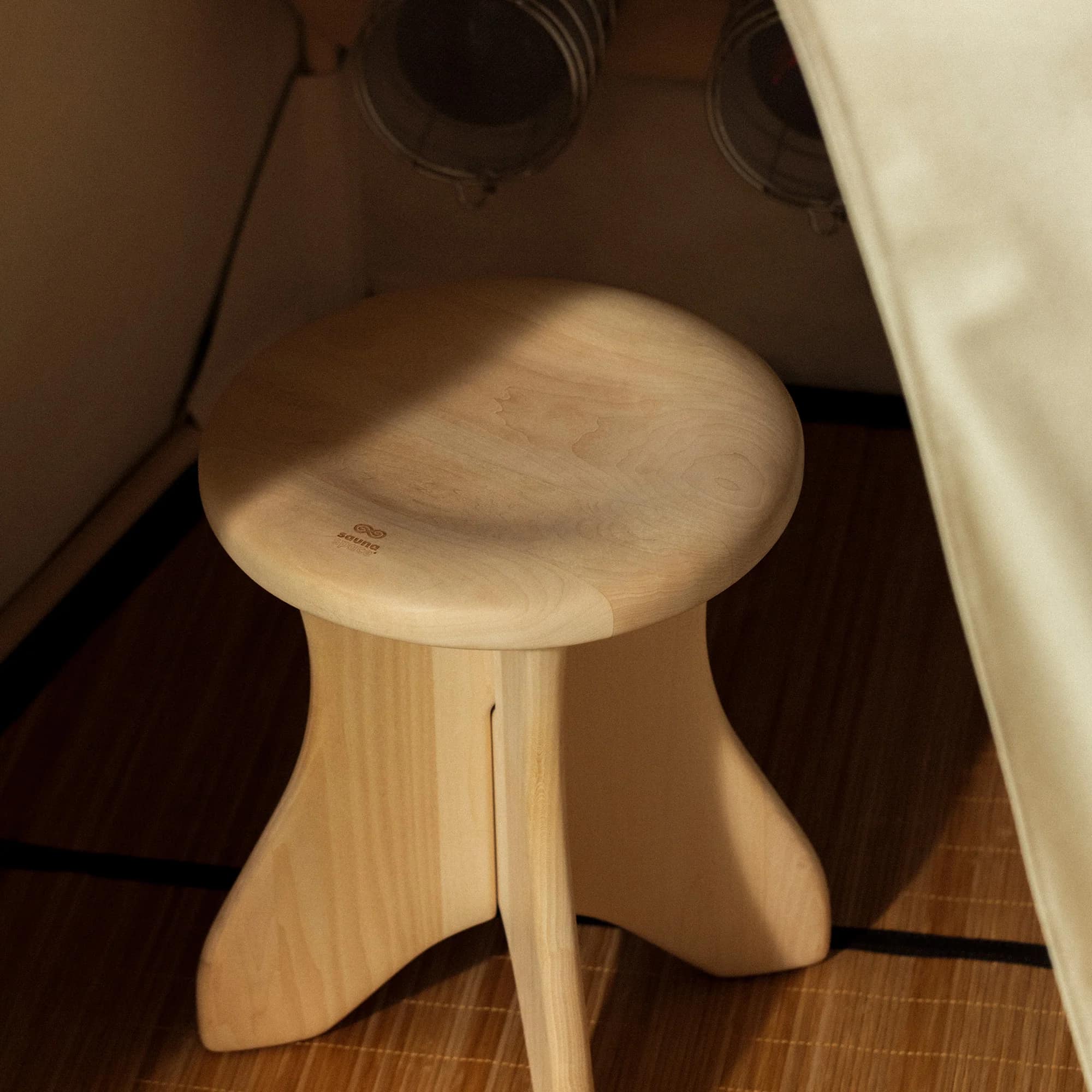The wooden stool on the bamboo floor mat inside a FireLight sauna