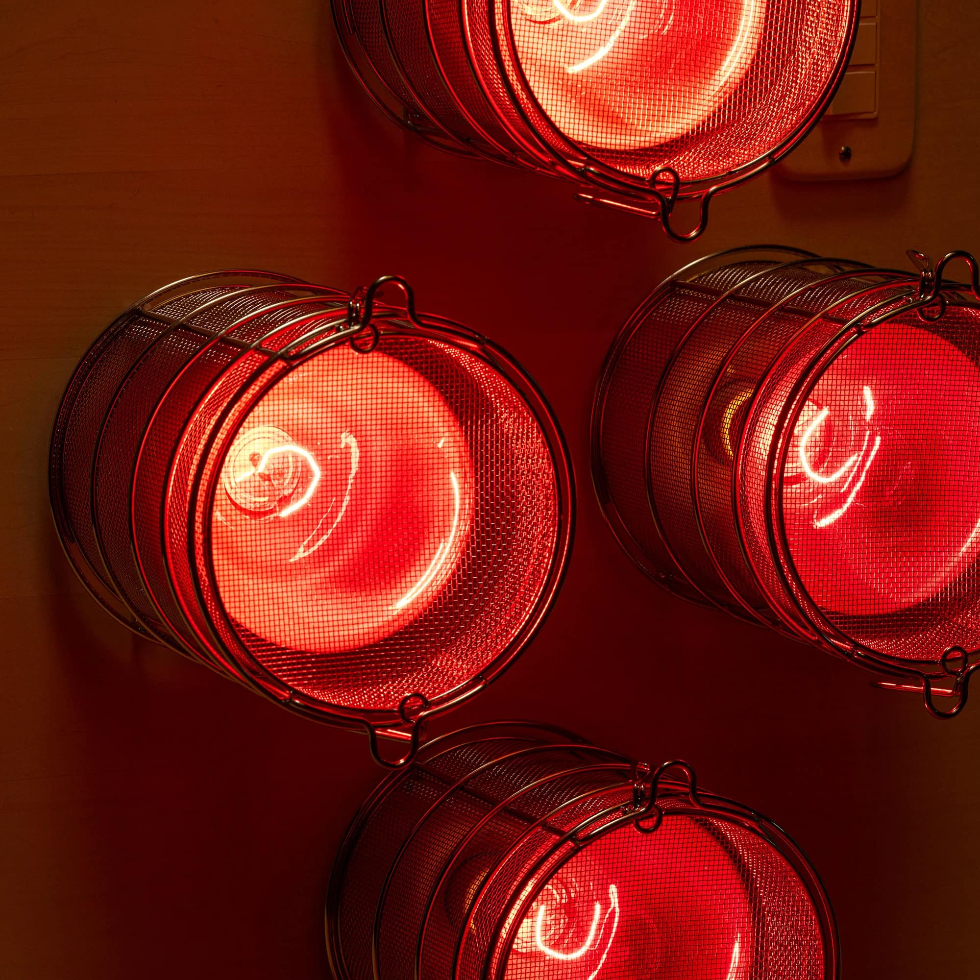 Close-up of glowing incandescent bulbs inside their wire guards on the FireLight's heater panel