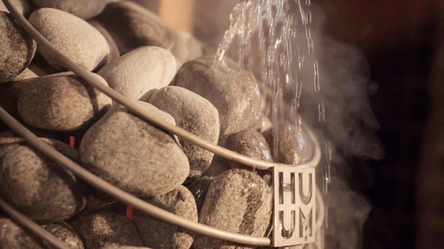 Steam rising from water splashed over the rounded stones of a HUUM DROP