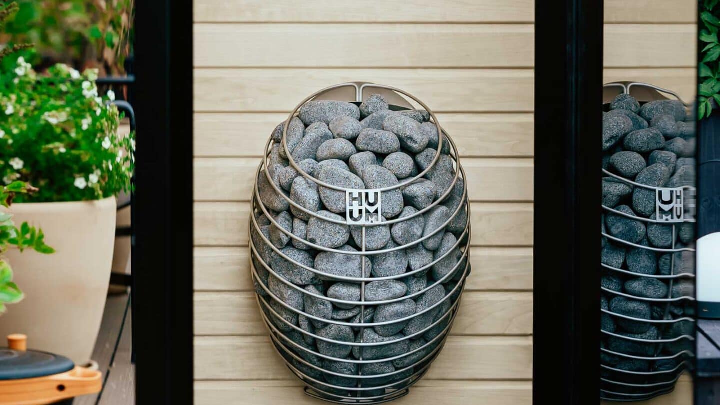 HUUM DROP mounted on a pale wood wall inside an open sauna doorway