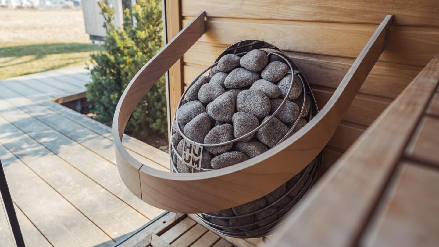 HUUM DROP inside its curved wooden guard beside a bench with a deck visible through the glass